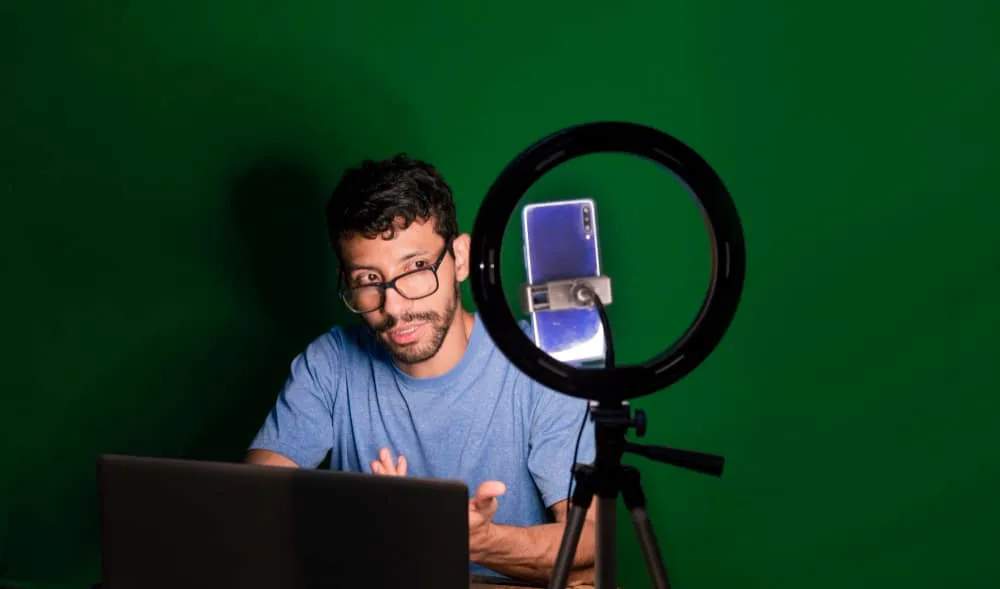 Young man with laptop making video blog young man creator contents with celphone